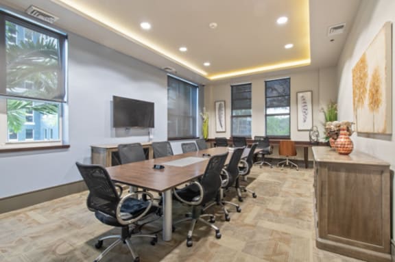 a conference room with a table and chairs and a television at One Plantation in Plantation, FL 33324