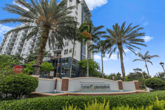 a large apartment building with palm trees in front of it at One Plantation in Plantation, Florida 33324