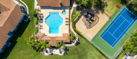 an aerial view of a house with a pool and a tennis court