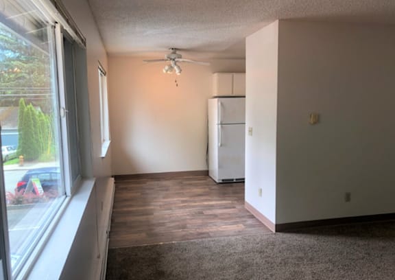 A room with a window, a ceiling fan, and a refrigerator.