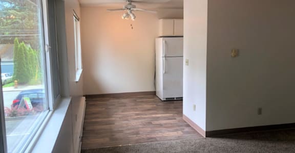 A room with a window, a ceiling fan, and a refrigerator.