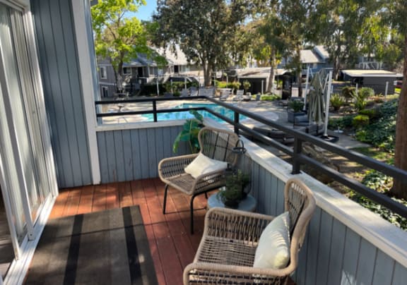 a balcony with two wicker chairs and a swimming pool