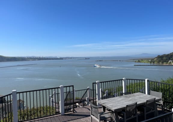 a deck with a table and chairs overlooking the water and a boat