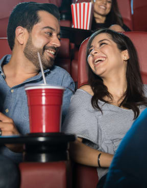 a couple at a movie theater smiling at each other