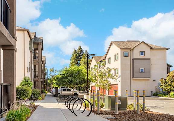 A sidewalk runs through a residential area with apartment buildings on either side.
