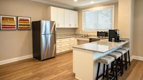A kitchen with a stainless steel refrigerator and a granite countertop.