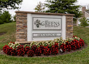 Thumbnail 2 of 6 - A sign for The Greens at Rolling Road stands in front of a house.