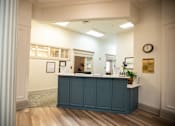 Thumbnail 5 of 31 - A reception area with a blue counter and a clock on the wall.