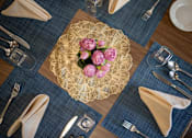 Thumbnail 10 of 31 - A table setting with a gold plate and pink flowers.