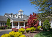 Thumbnail 3 of 31 - A house with a white fence and a red tree in front.
