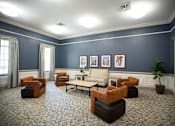 Thumbnail 13 of 31 - A living room with a patterned carpet and a variety of seating options.