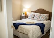 Thumbnail 15 of 31 - A bed with a blue blanket and a book on it.