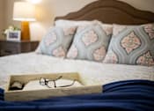 Thumbnail 17 of 31 - A pair of glasses sits in a wooden box on a bed.