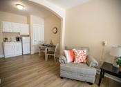 Thumbnail 19 of 31 - A living room with a grey couch and a wooden table.