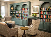 Thumbnail 11 of 31 - A room with two chairs and a table in front of a bookshelf.