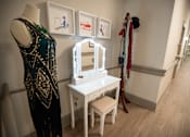 Thumbnail 27 of 31 - A white vanity table with a mirror and a black dress on a mannequin.