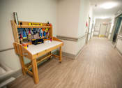 Thumbnail 26 of 31 - A long hallway with a bench and a table with various items on it.