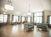 Thumbnail 23 of 31 - A spacious living room with grey couches and wooden floors.