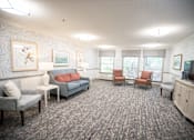 Thumbnail 19 of 29 - A living room with grey carpet and furniture.at Spring Arbor of Wilson, Wilson, NC