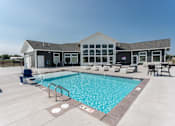 Thumbnail 1 of 11 - A large swimming pool with a building in the background.