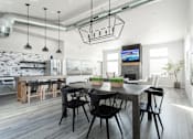 Thumbnail 3 of 8 - A modern dining room with a wooden table and chairs.