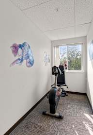 A person is working out on a stationary bike in a room with artwork on the wall.