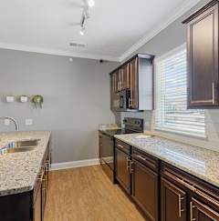 a kitchen with granite countertops and dark wood cabinets
