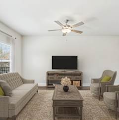 a living room with a couch and chairs and a tv
