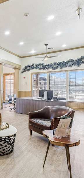 A large room with leather chairs and a table with a bottle on it.