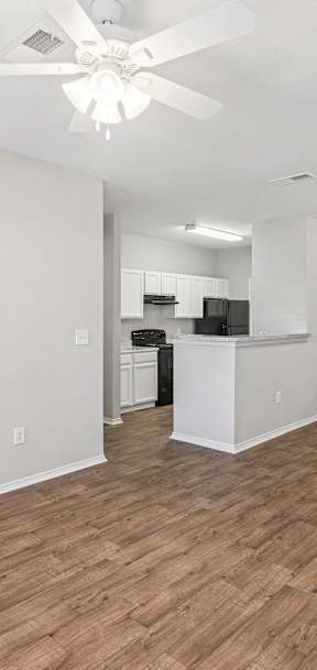 A black stove in a kitchen with white cabinets.