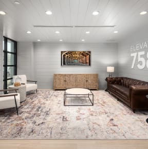 a living room with a brown leather couch and two white chairs