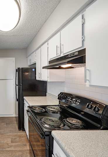 A kitchen with a black stove top oven and a black refrigerator.