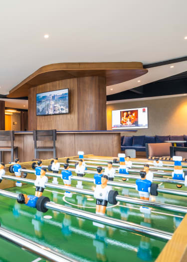 a game room with foosball tables and televisions