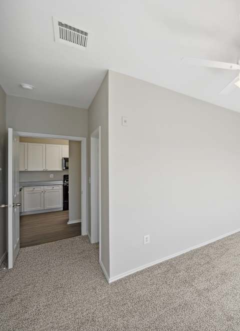 A room with a ceiling fan and a window letting in sunlight.