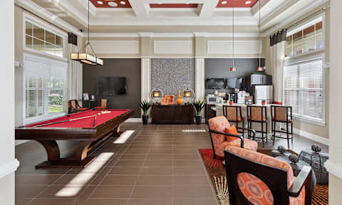 A room with a pool table and a bar area.