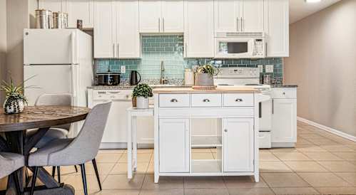 A kitchen with white cabinets and a white fridge.