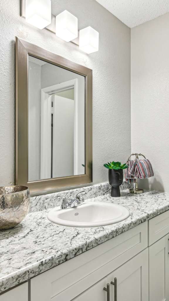A bathroom with a marble countertop and a large mirror.