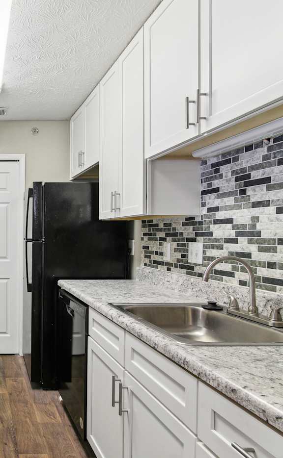 A kitchen with black appliances and white cabinets.