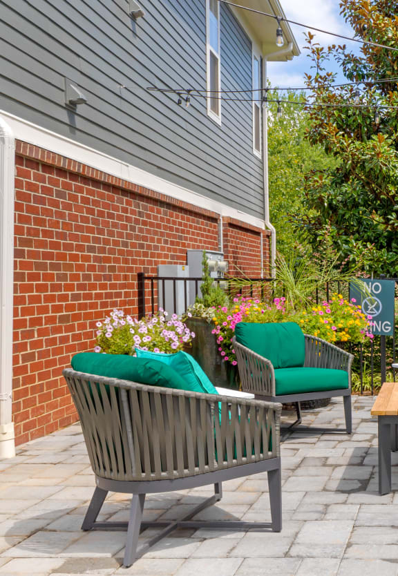 a patio with chairs and a table in front of a brick building
