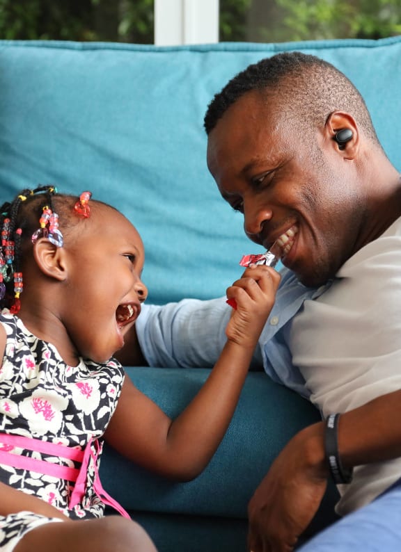 a father playing with his daughter on a couch