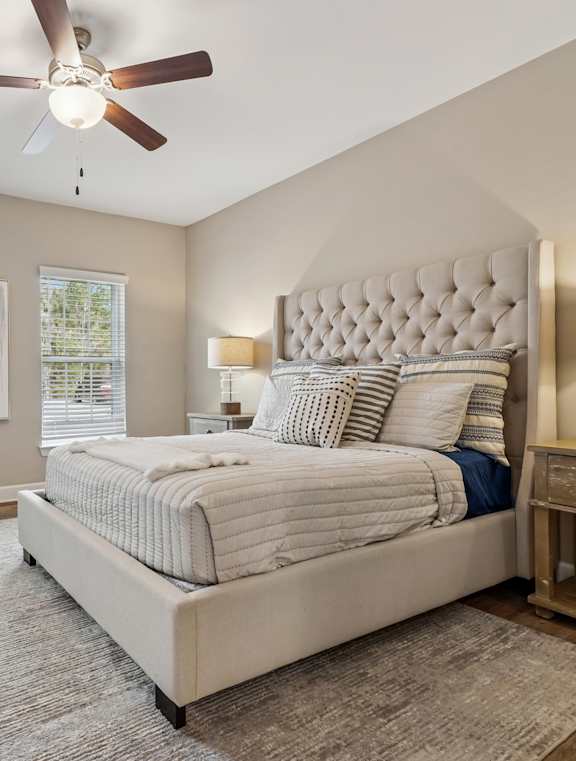 A bedroom with a large bed, a dresser, and a ceiling fan.