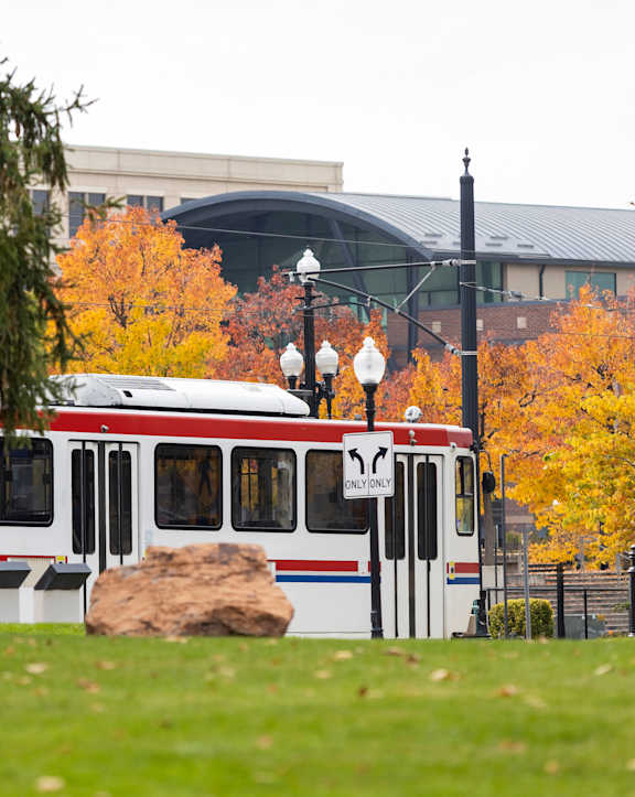 A red and white train is on a track in a grassy area. at Liberty Blvd Apartments - Saltlake City, UT Apartments, Saltlake City, UT, 84102