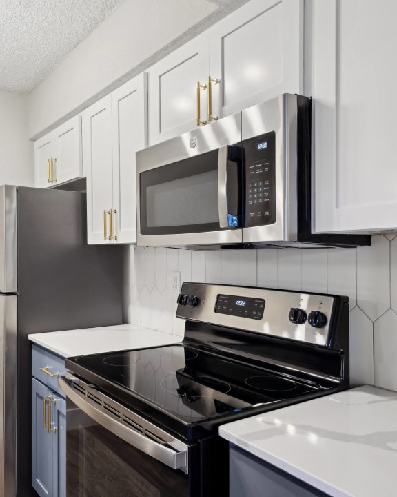 a kitchen with white countertops and stainless steel appliances