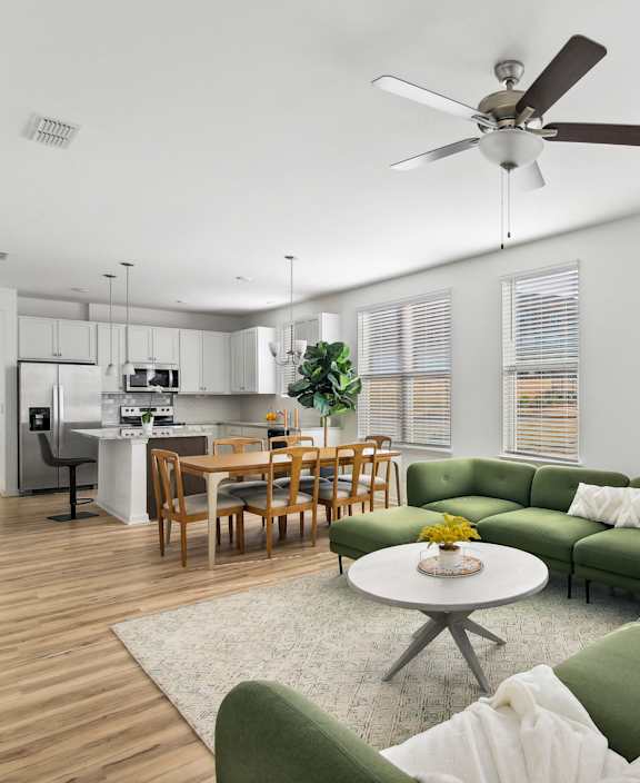 a living room with a green couch and a ceiling fan