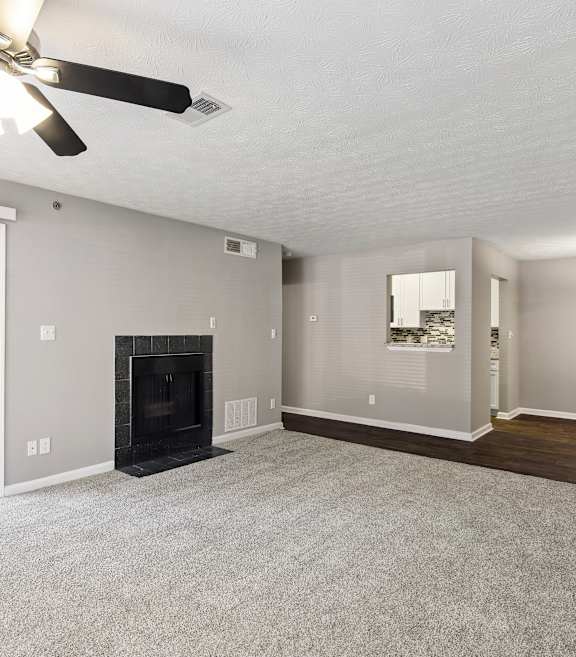 A living room with a fireplace and a ceiling fan.