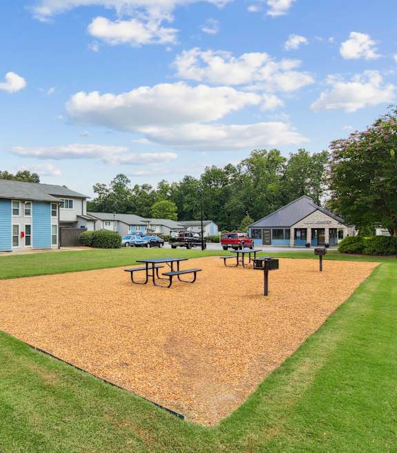 A park with a playground and picnic tables.