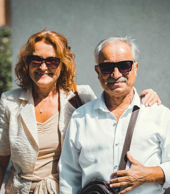 A man and a woman are standing outside, both wearing sunglasses.