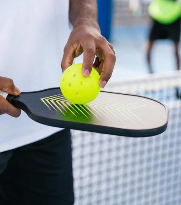 A person holding a tennis racket and ball on a tennis court.
