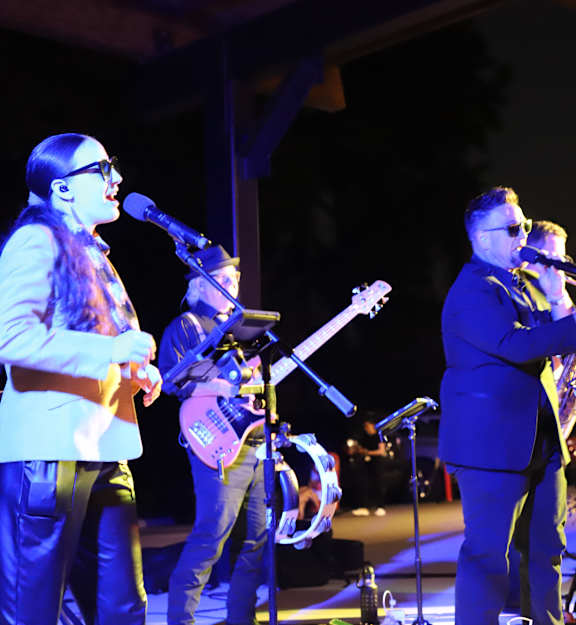 A band performing on stage with a female lead singer.