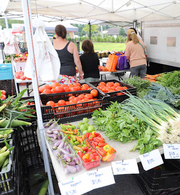 A market stall with vegetables on display and people shopping.